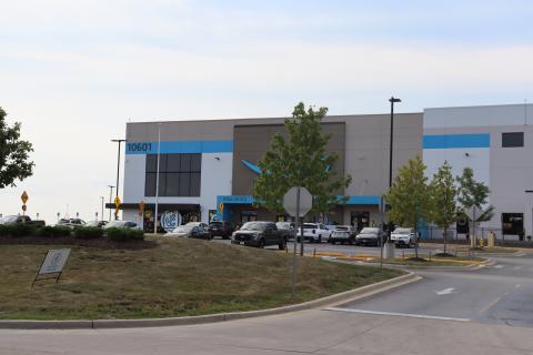 The exterior of the Amazon warehouse where the fire occurred is pictured along with workers milling about outside. 