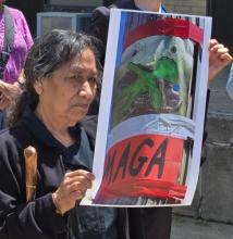 An unidentified woman holds a photo of an anti-immigrant poster. 