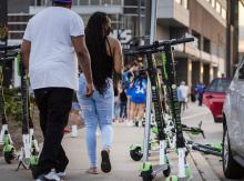 People walk past electric scooters parked on a sidewalk Wednesday, June 23, 2021, in downtown Milwaukee, Wis. Angela Major/WPR