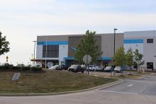 The exterior of the Amazon warehouse where the fire occurred is pictured along with workers milling about outside. 